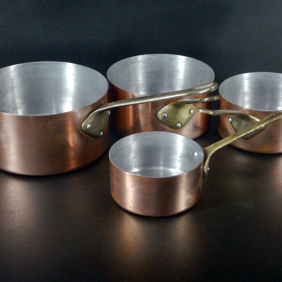 Complete set of four well loved copper covered aluminium sauce pans